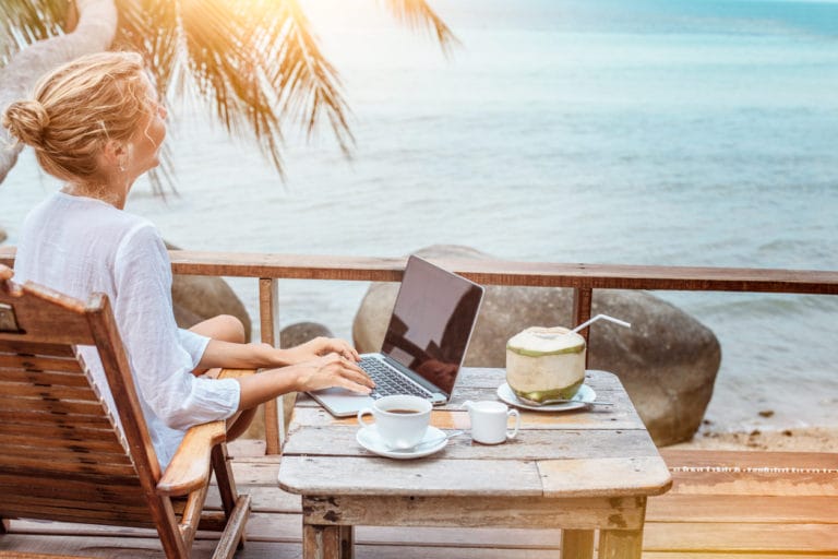 Young woman working on her laptop outside while on vacation