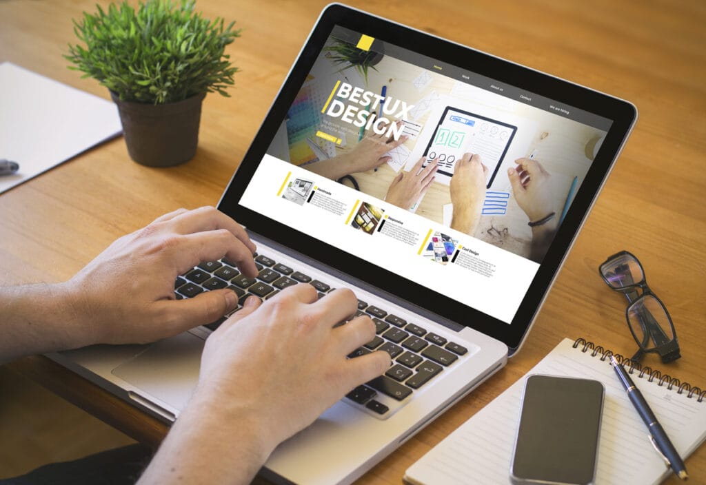 Top view of a man's hands working on a laptop featuring a website