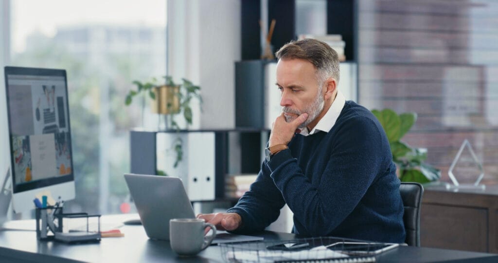 Businessman checking various websites on his laptop in his office