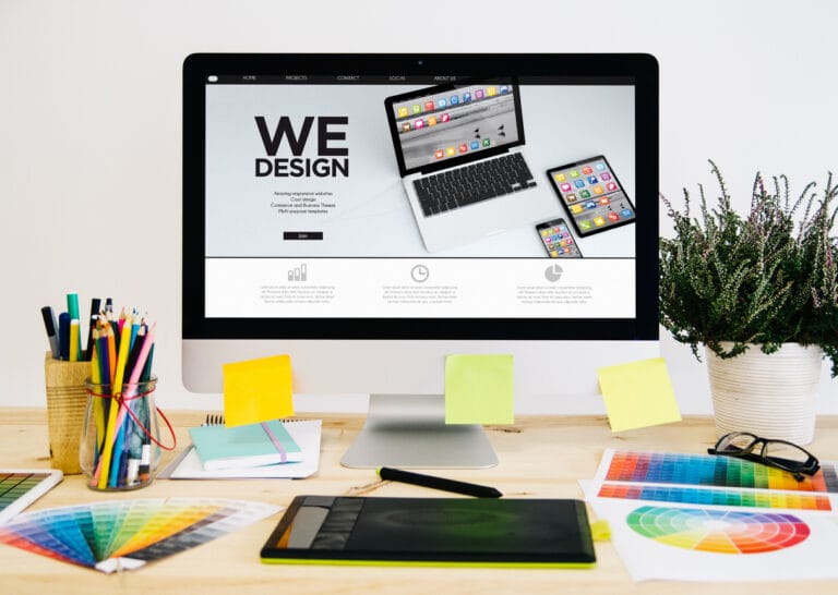 A desktop with design essentials, graphic tablet, and computer monitor showing headless WordPress website design