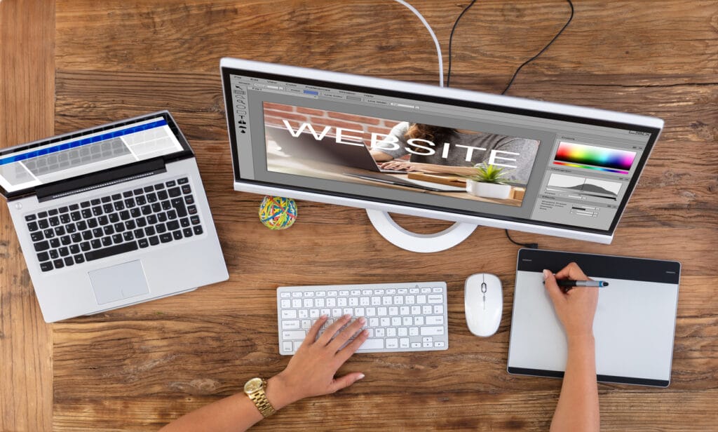 Laptop, monitor, and female designer's hand using graphic tablet and collaboration tools with Agile for website development