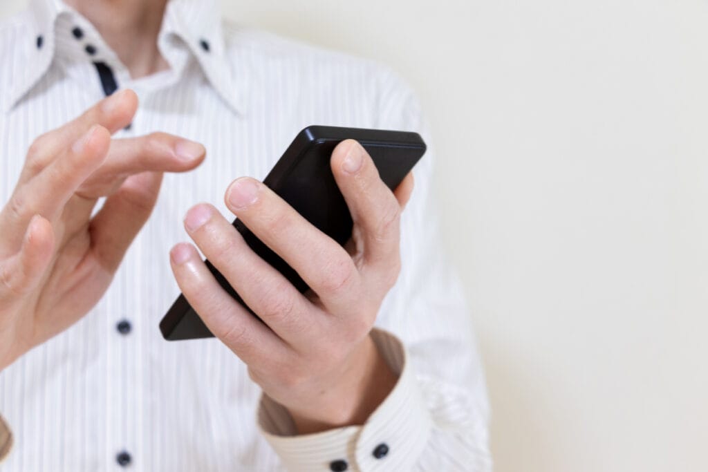 PWA for WordPress: Cropped shot of a man in a white shirt checking a website on his mobile phone