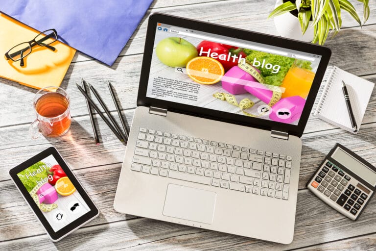 Health and wellness content: A laptop and phone on a table with a health blog displayed on the screen