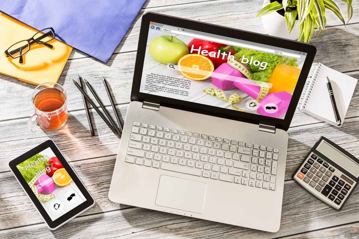 Health and wellness content: A laptop and phone on a table with a health blog displayed on the screen